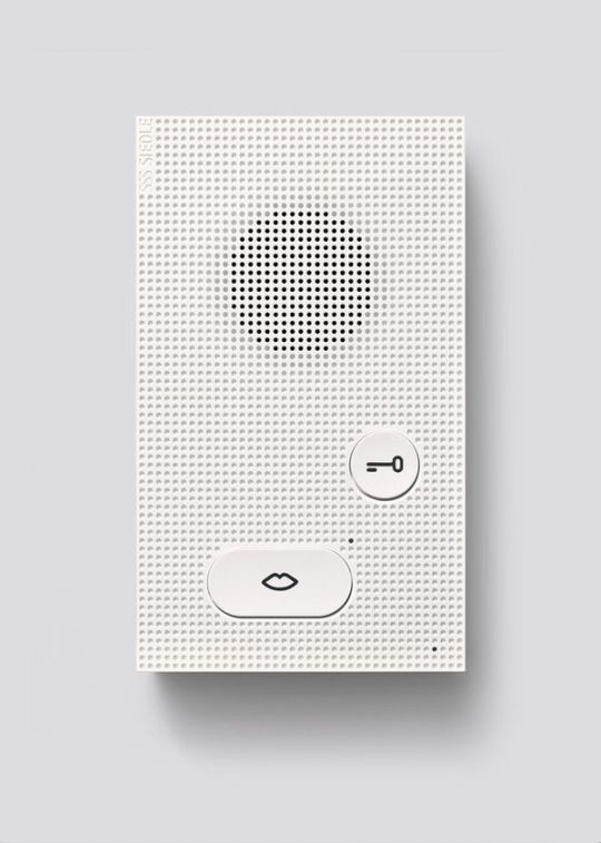 The image displays a minimalist, textured white panel featuring a grid pattern and a central circular array of small dots, suggesting a technical or tactile interface element. The design emphasizes subtlety and precision through its monochromatic palette and clean geometric arrangement.