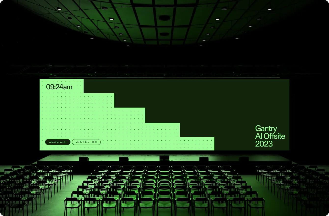 The image depicts a large, dark, modern auditorium or conference hall set up for an event. The design utilizes strong geometric lines and a monochromatic, deep green palette to create a sophisticated, focused, and professional atmosphere.