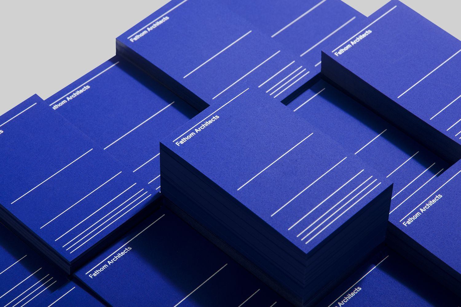 A sophisticated isometric arrangement of stacked business cards or printed materials in deep cobalt blue with minimalist white line details. The design showcases a modern, premium aesthetic with careful attention to shadow, depth, and geometric composition that emphasizes luxury and professionalism.