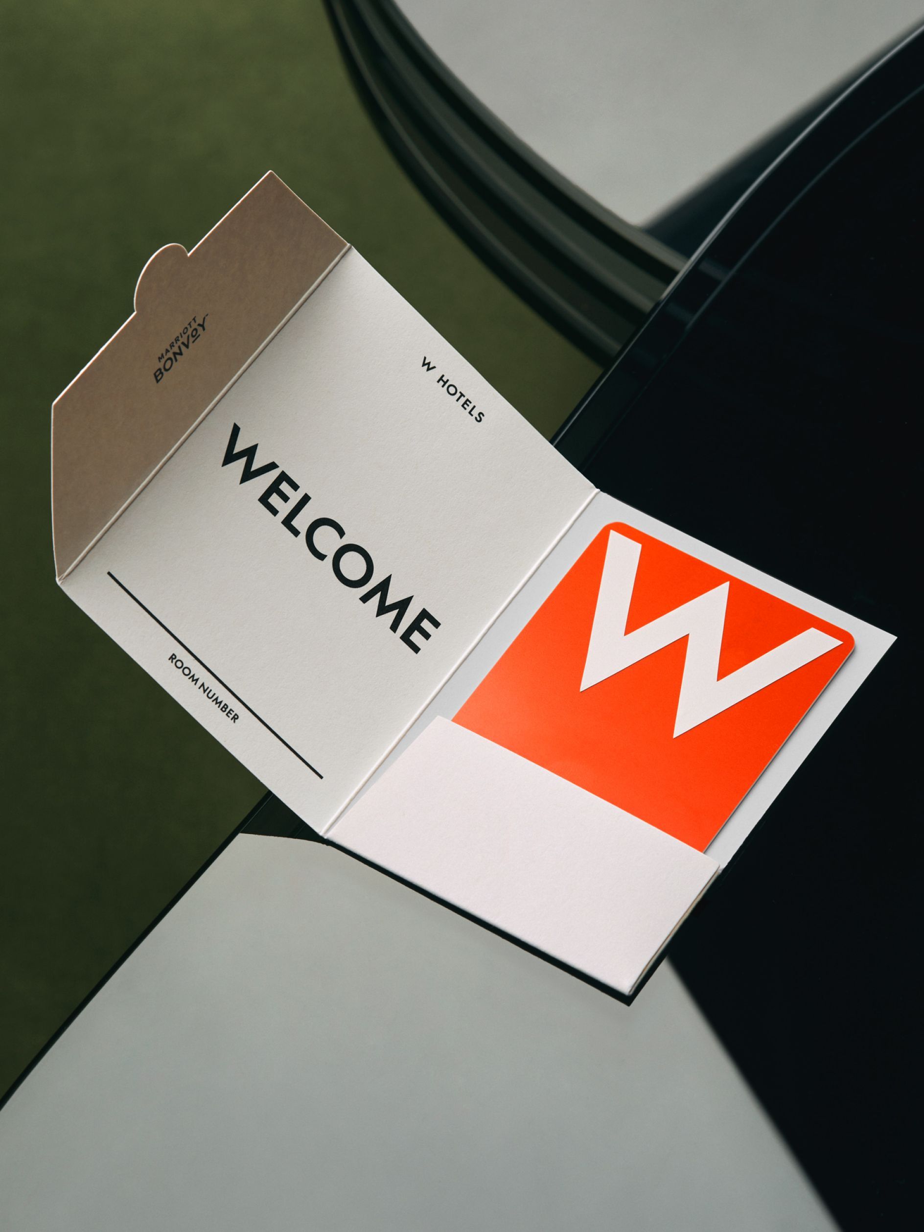 This image features a minimalist and sophisticated welcome card design, utilizing clean lines and negative space to convey a sense of modern luxury. The composition is sharp and balanced, relying on the contrast between muted neutrals and a vibrant accent color.