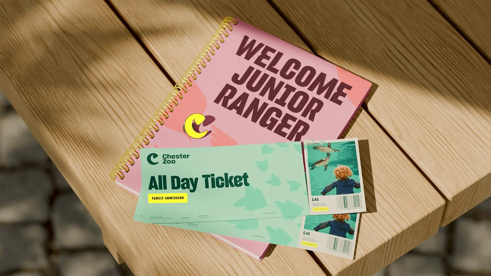 This visual display utilizes a clean, functional design centered around promotional tickets and informational materials. The layered composition features bright pink headers contrasted with soft greens, set against a warm, natural wooden background. The overall aesthetic is crisp and professional, appealing directly to an audience interested in wildlife experiences and organized activities.