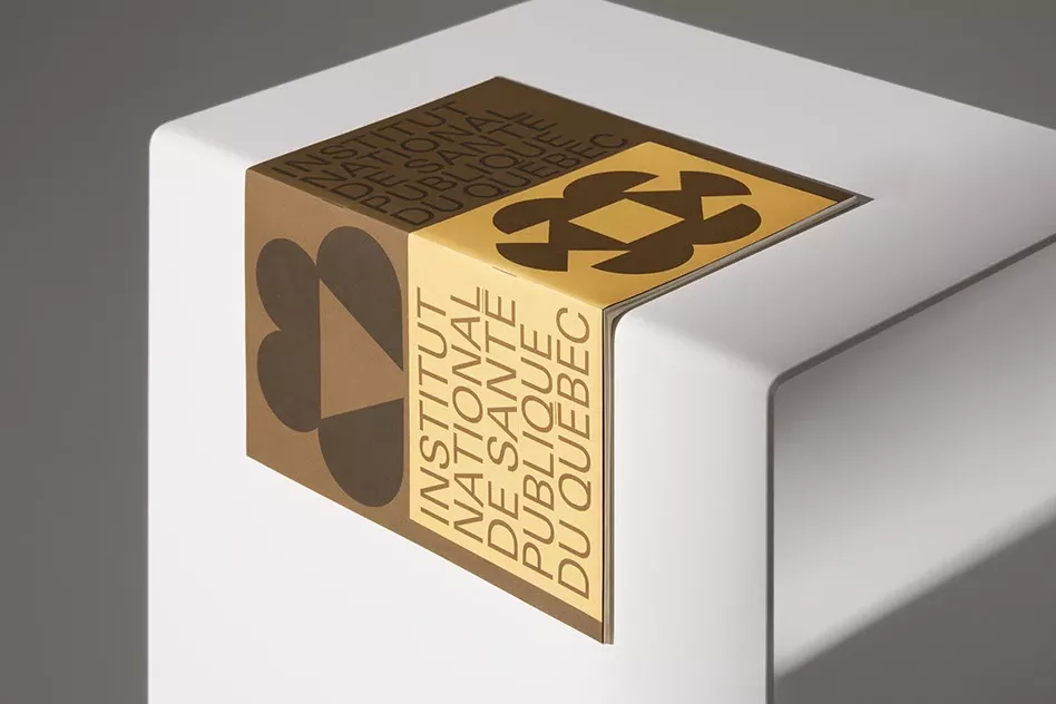 The image presents a clean, minimalist design featuring a rectangular plaque or sign mounted on a white surface. The design utilizes warm gold tones against the stark white background, suggesting institutional authority and refined simplicity.