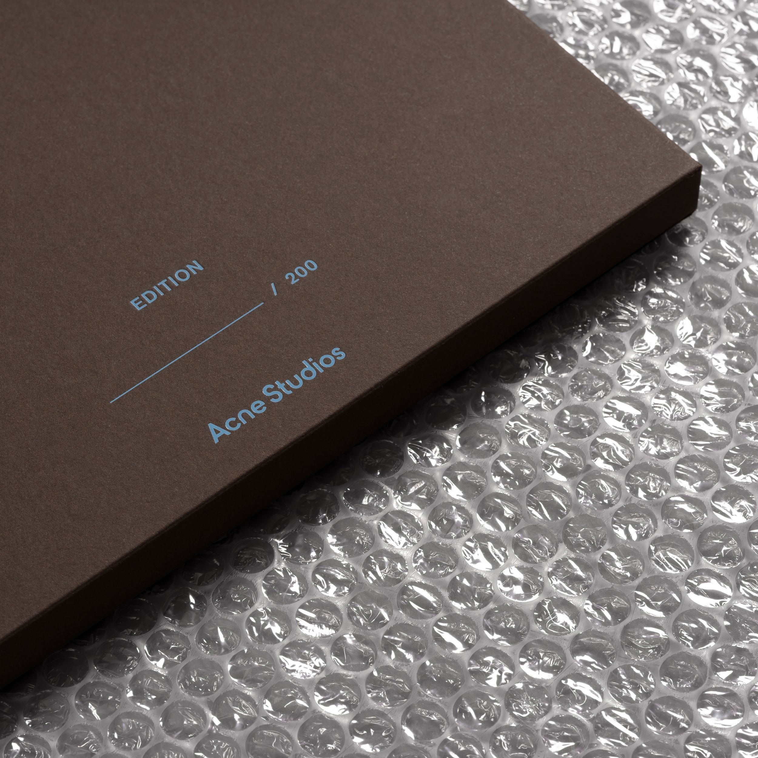 The image features a minimalist product box with a matte brown finish, suggesting a premium or sophisticated aesthetic. The clean lines and subtle typography convey a sense of understated elegance and modern design.
