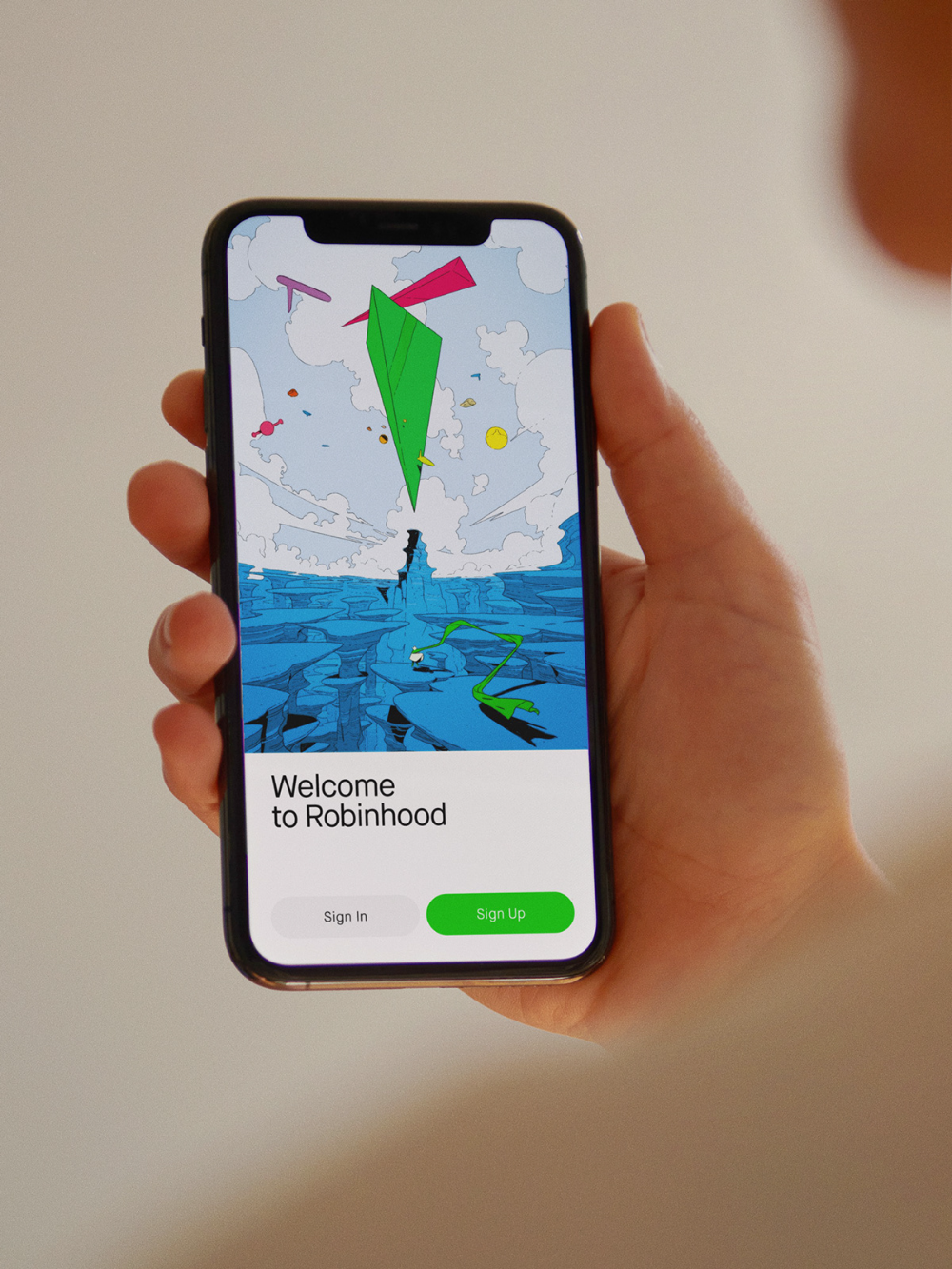 The image displays a mobile application interface featuring a whimsical, nature-inspired illustration set against a light blue sky and sea backdrop. The design employs a clean, flat graphic style with vibrant pops of color for the elements like the green parachute. The overall feel is inviting, playful, and serene.