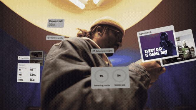 The image presents a dark, focused scene featuring a person interacting with a holographic or augmented reality interface, suggesting a high-tech, immersive experience. The visual language is dominated by deep blues and warm highlights, creating a moody and futuristic atmosphere.