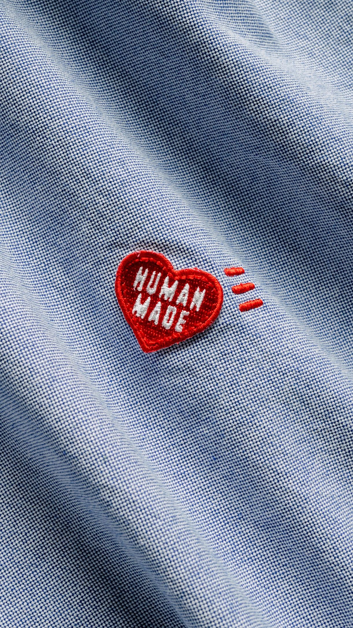 This image captures a tactile study of indigo fabric featuring a handcrafted heart tag, emphasizing natural texture and simple, honest labeling. The visual language is minimalist and artisanal, relying on the quality of the material and the sincerity of the message to convey its aesthetic.