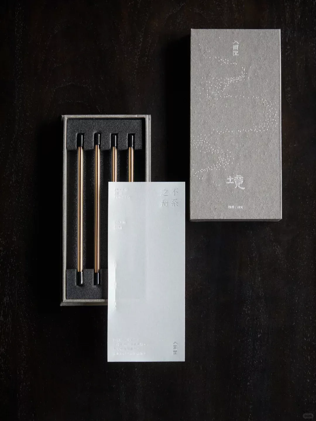 This image presents a minimalist and sophisticated product display, emphasizing clean lines, muted tones, and precise material execution. The design relies on negative space and the contrast between matte black surfaces and subtle, reflective metallic accents to convey a sense of premium quality and quiet elegance.