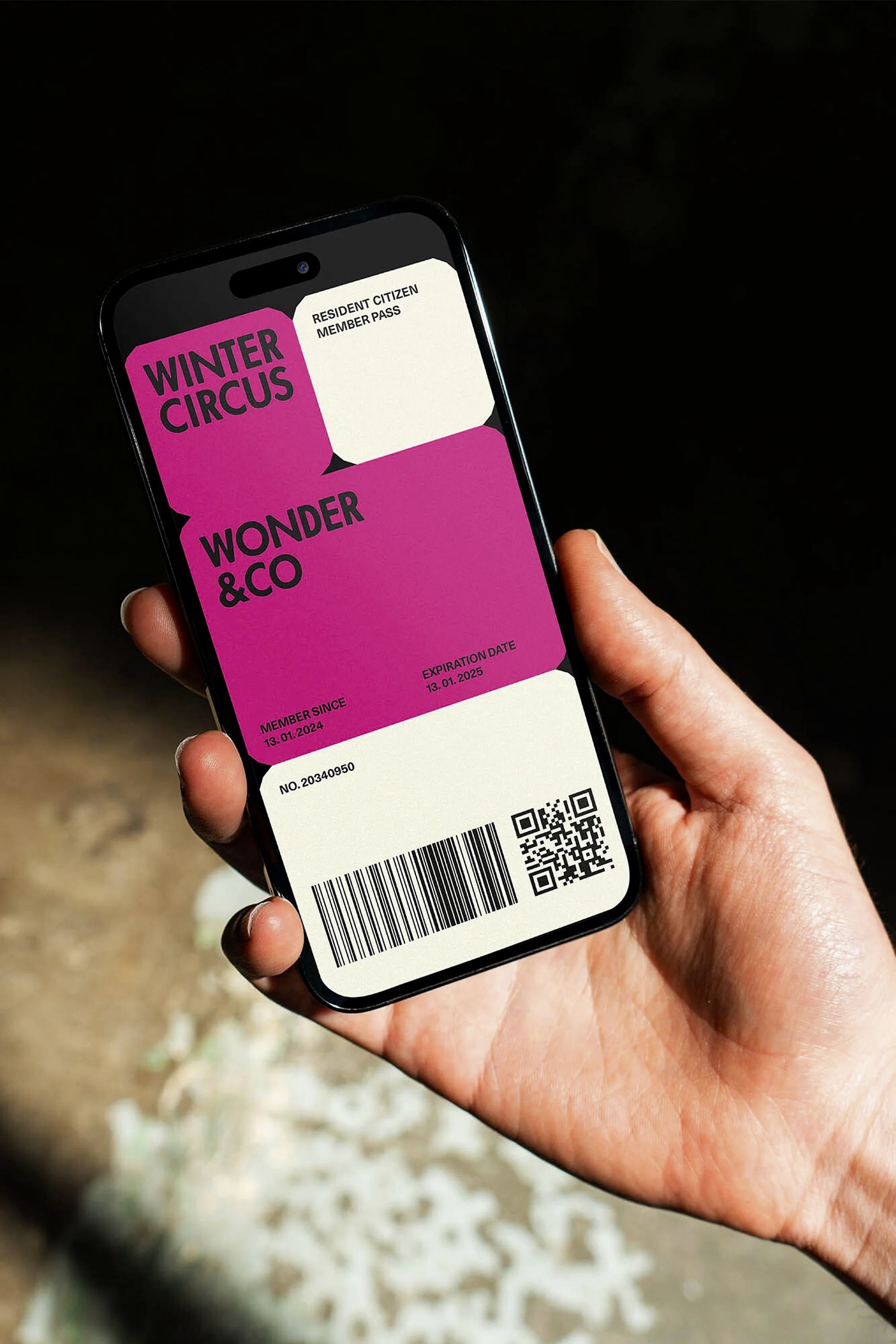 The image features a close-up of a hand holding a smartphone displaying a vibrant, modern membership card design. The design uses bold color blocking and clean typography to convey a sense of exclusive, perhaps whimsical, membership.