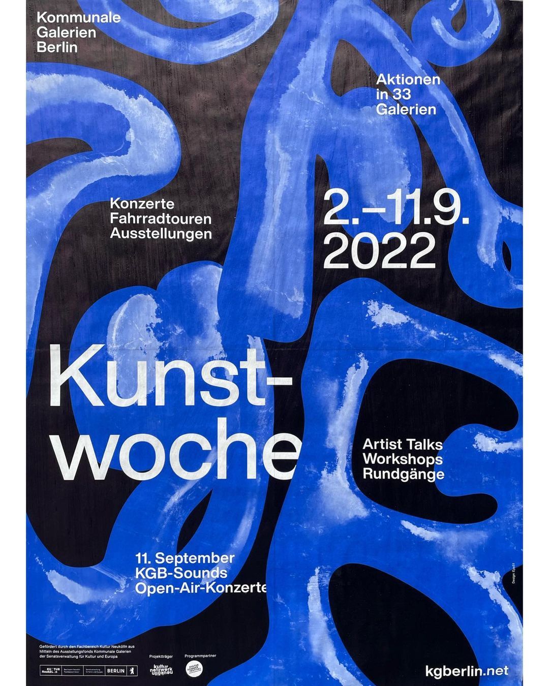 The poster utilizes a dynamic, fluid design dominated by sweeping, organic shapes in bright blue against a stark black background. The visual language is bold and energetic, effectively conveying the theme of an arts festival through movement and strong contrast.