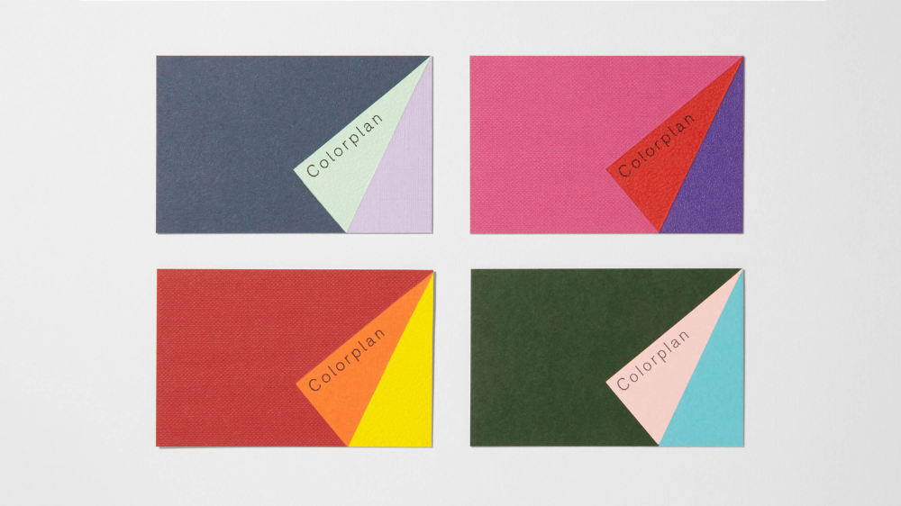A minimalist geometric composition featuring four rectangular cards arranged in a 2x2 grid, each displaying bold color-blocking with diagonal triangular elements and subtle text labels. The design employs a clean, contemporary aesthetic with sharp angles and a restrained color palette that creates visual rhythm through contrasting hues.