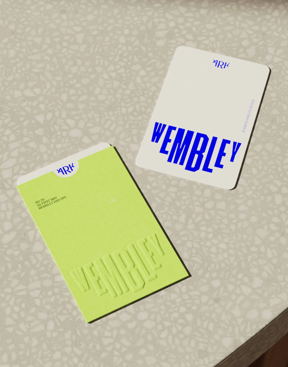 This image showcases a clean, modern approach to branding using high contrast between cool blues and vibrant lime green against a neutral background. The design emphasizes simplicity, clear typography, and tactile elements like embossing or color blocking to create a sophisticated yet fresh visual identity.