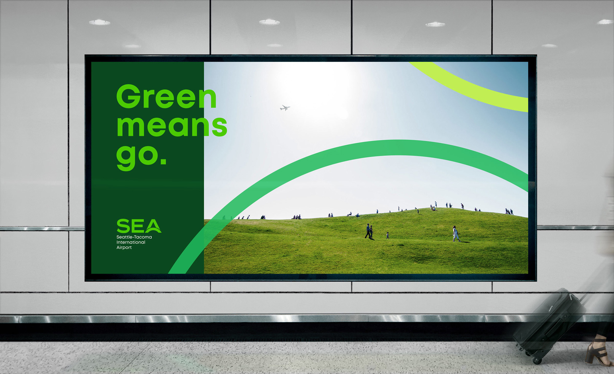 A modern environmental campaign billboard featuring bold typography and vibrant green branding against a serene landscape photograph. The design uses a split composition with a dark green text panel on the left and a panoramic nature scene on the right, connected by flowing curved graphic elements. The aesthetic is contemporary and purpose-driven, emphasizing sustainability and ecological messaging.