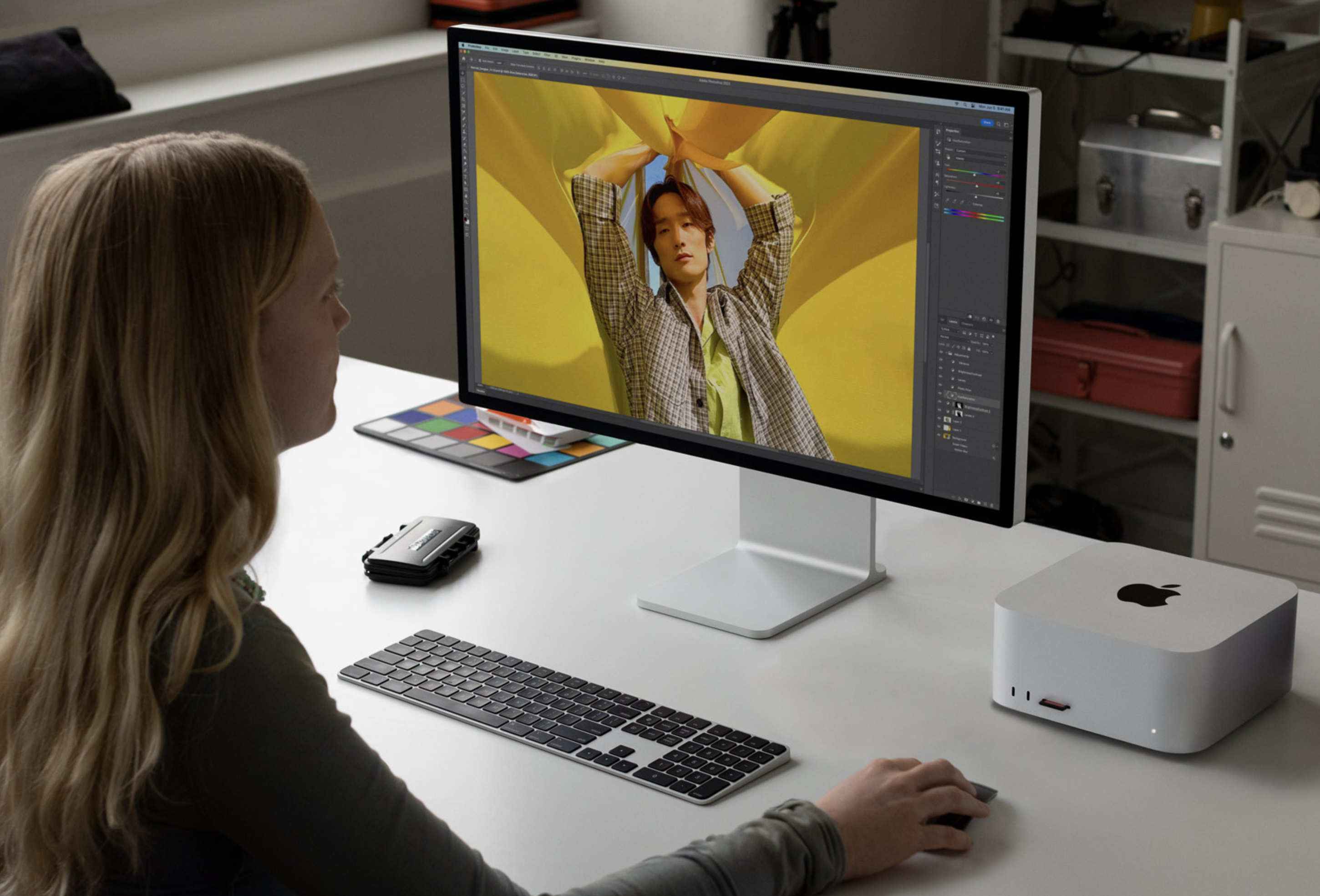 This image captures a focused moment of digital creation, showcasing a modern workspace dominated by a large monitor displaying vibrant graphic work. The visual language is clean and professional, emphasizing technology and creative output in a bright, organized environment.