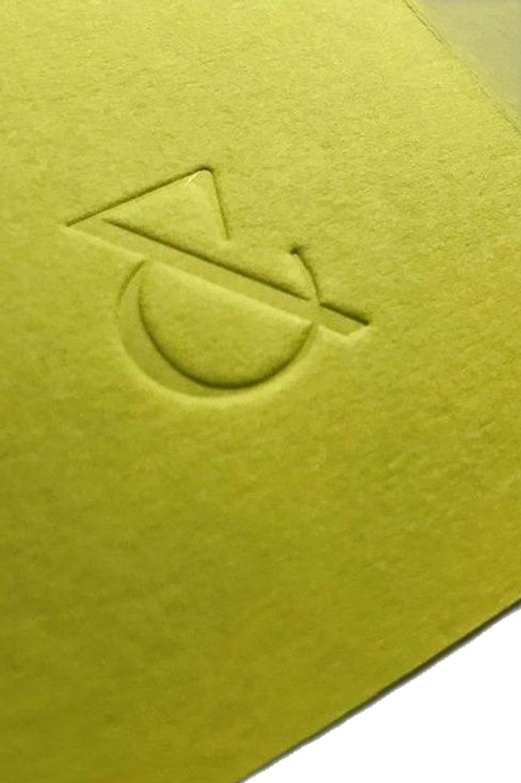 This design utilizes a subtle tactile quality through debossing on a smooth, pale yellow surface. The visual language is minimalist and clean, relying entirely on the negative space and the precise execution of the graphic mark. The overall feel is sophisticated, quiet, and focused on quality assurance.