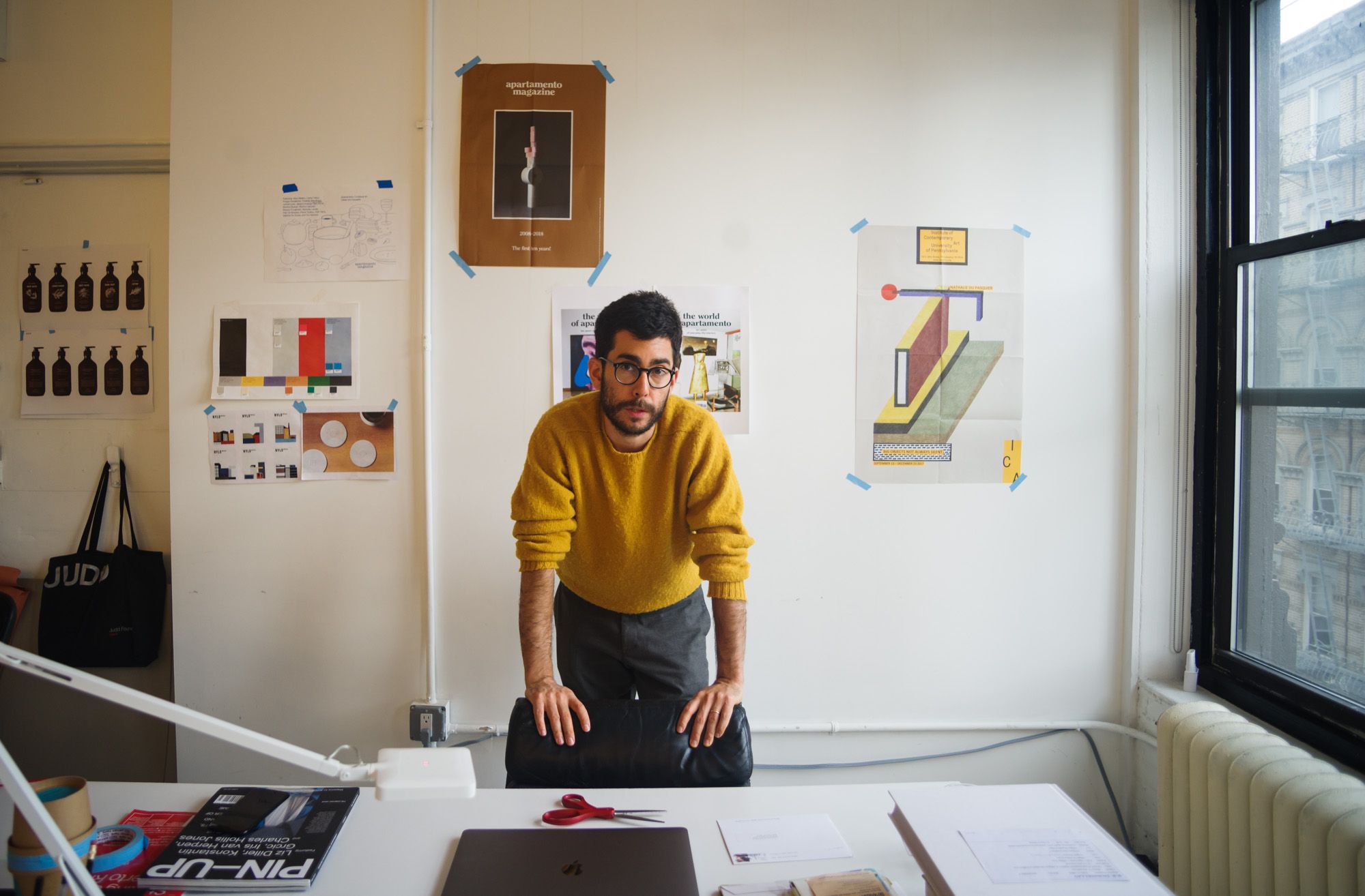 This image captures a creative workspace characterized by a blend of personal artistic display and professional documentation. The visual language is clean and academic, utilizing simple geometric elements and layered paper displays against a minimalist white backdrop. The overall feel is one of focused, thoughtful design work.