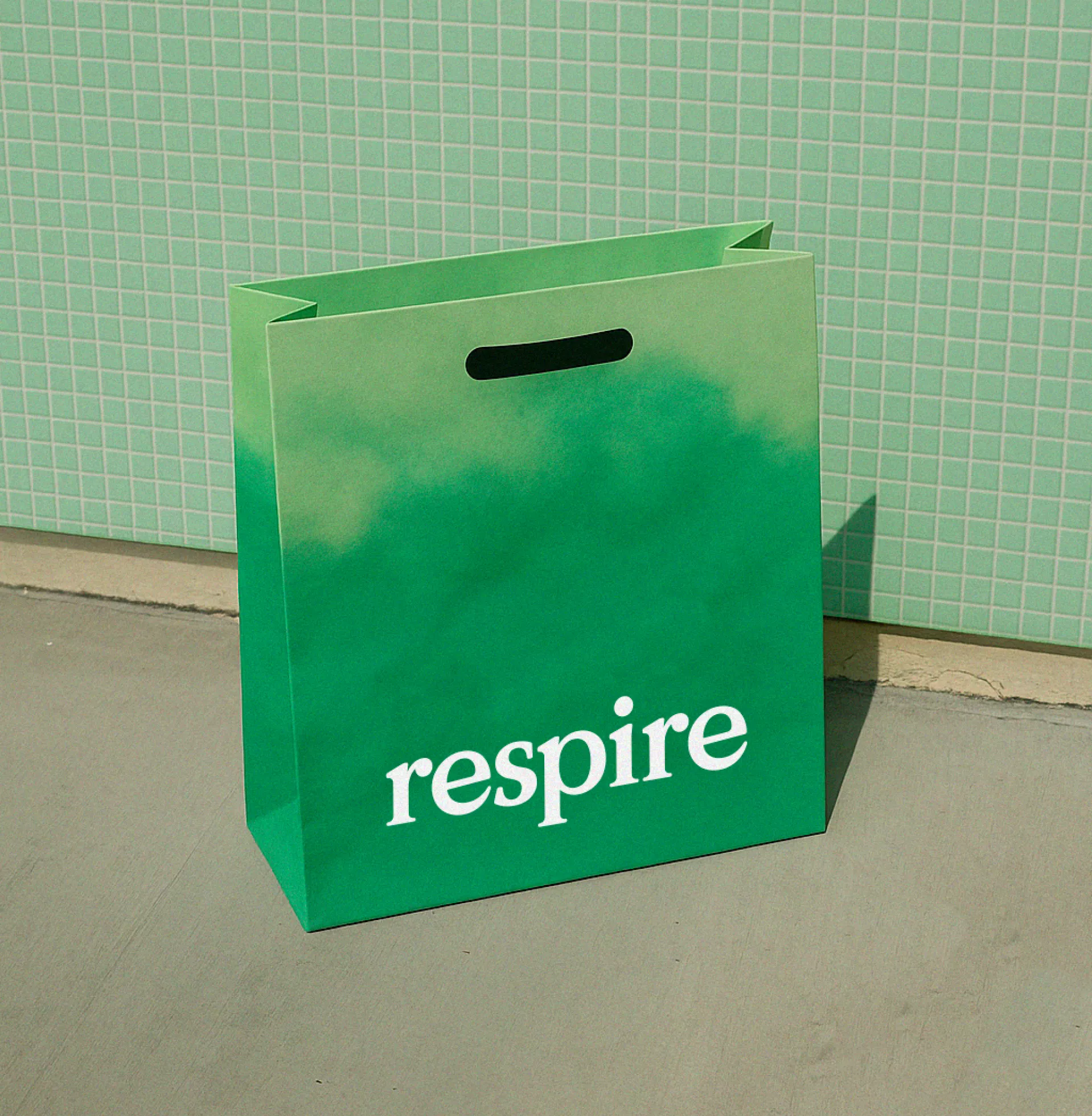 This image features a simple, matte green paper bag with a subtle gradient effect, suggesting freshness or nature. The design is minimalist and clean, relying on solid color blocking and clear, modern typography to convey a sense of organic well-being.