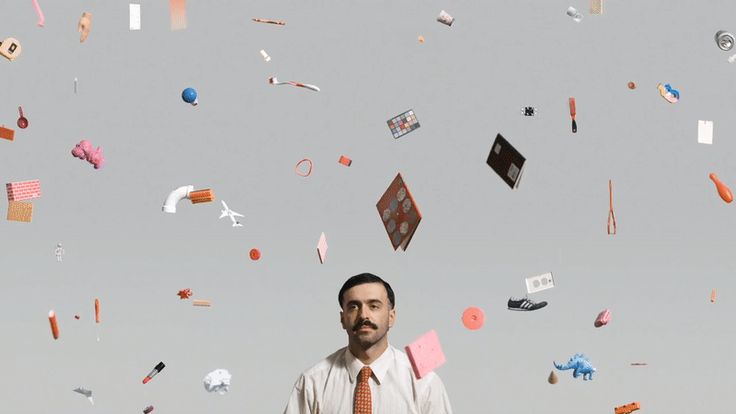 This image presents a high-key, minimalist composition featuring numerous small, scattered paper or card-like objects floating against a light gray background. The visual language is clean and sparse, emphasizing texture and the interplay between solid forms and negative space.