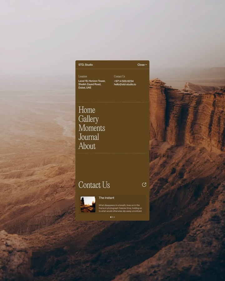 The image presents a minimalist, earthy aesthetic dominated by warm, muted tones and rugged textures. The design uses ample negative space to focus attention on a clean, dark-toned informational panel set against a vast, arid landscape backdrop.