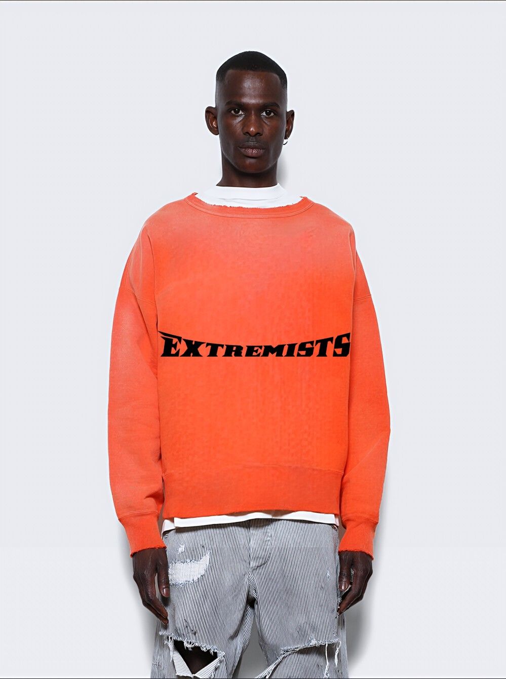 This image showcases a striking blend of casual streetwear with an edgy, rebellious aesthetic through bold color blocking and distressed denim. The visual language relies heavily on high contrast between the vibrant orange garment and stark black typography, creating a strong statement piece. The overall feel is confident, contemporary, and slightly aggressive.